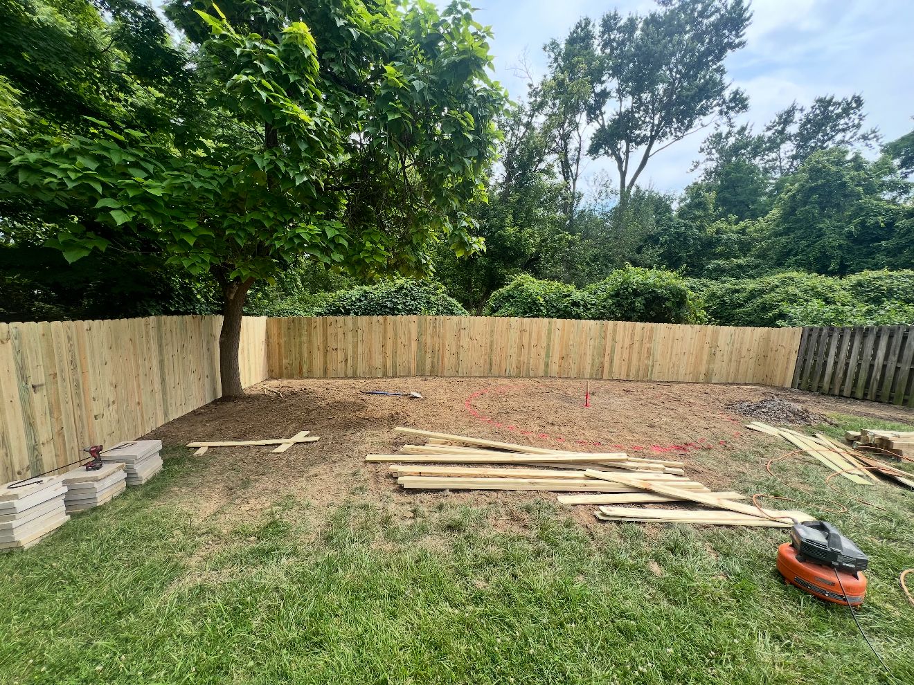 Privacy fence going up with lumber staged in the yard